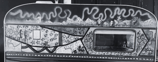 Schwarz weiß Fotografie: Ein Oldtimer-Wohnwagen mit abstrakten und blumigen Motiven auf der Seite, mit einem Fenster und dekorativen Mustern.