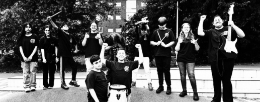 Schwarz weiß Fotografie der Band Golden Eagels. Die Schulband der Oberschule Oslebshausen haben teilweise ihre Instrumente noch in der Hand (Trommel, Bass). Sie jubeln uns gucken grinsend in die Kamera.